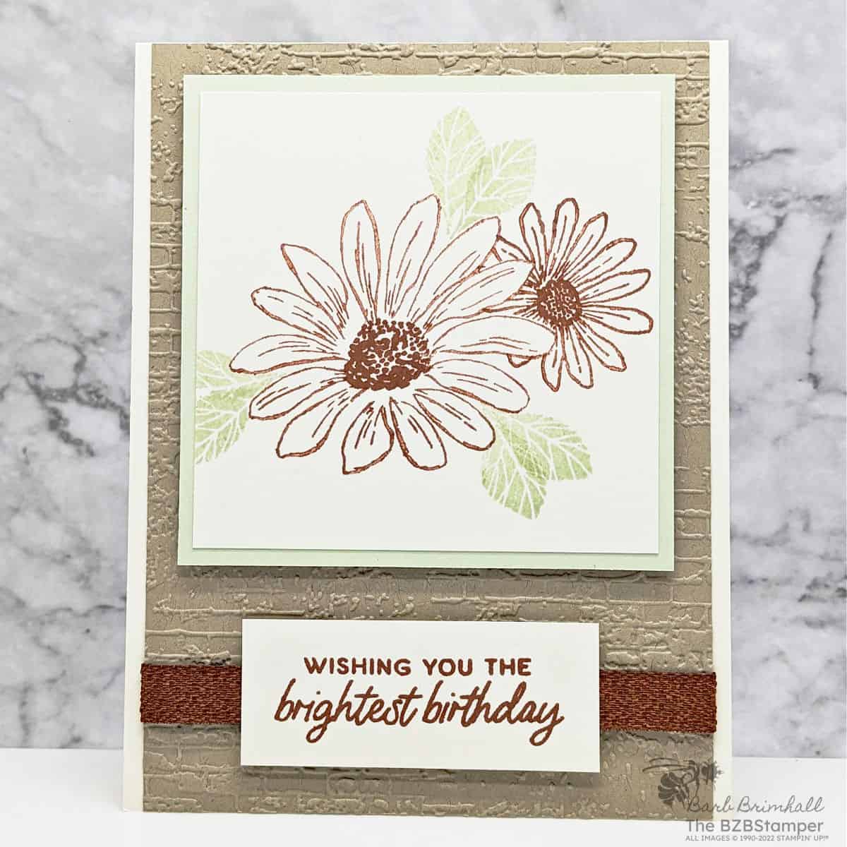Cheerful Daisies Birthday Card 1 Cheerful Daisies Birthday Card in kraft and green, with an embossed background and ribbon.