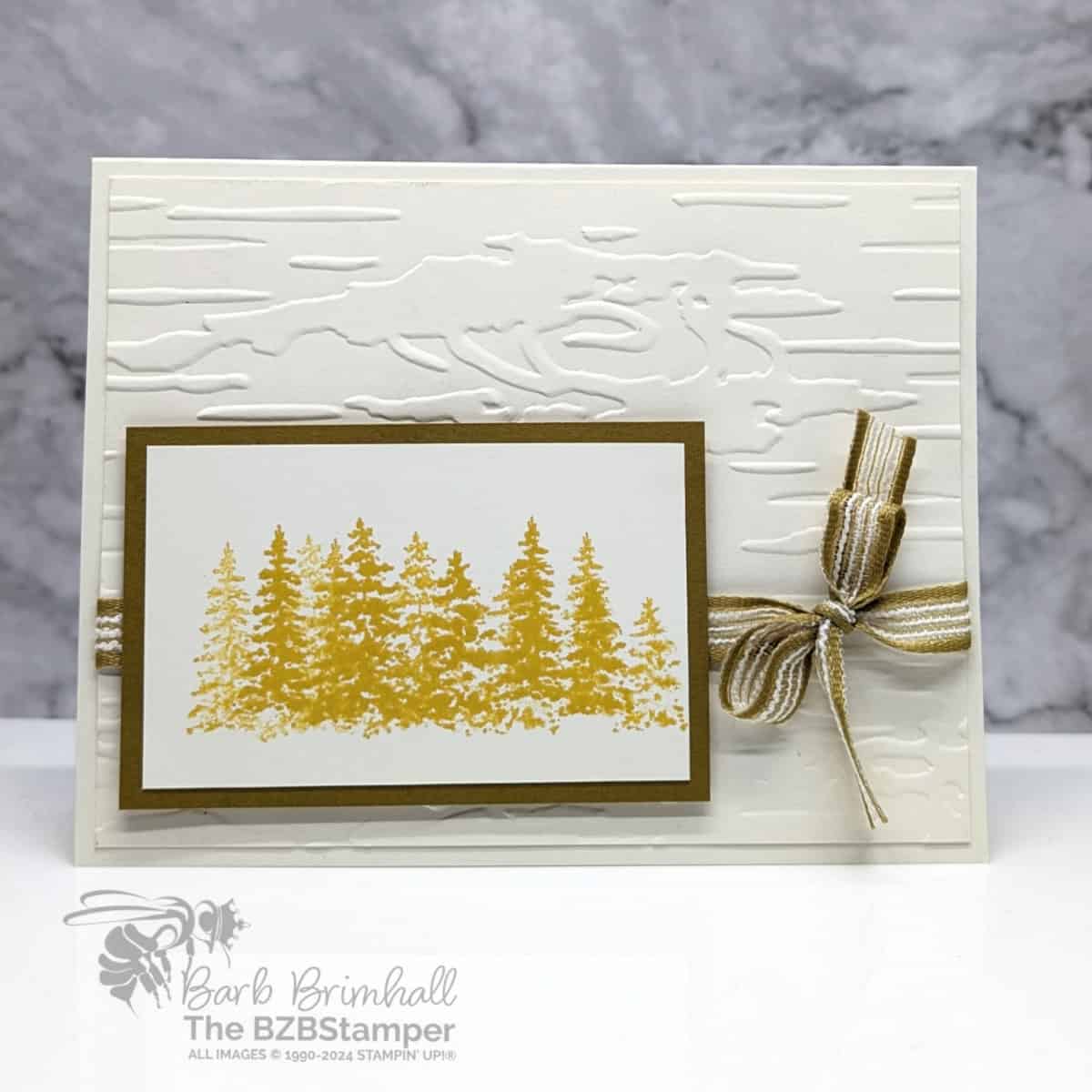 Peaceful Evergreens Masculine Card 1 Peaceful Evergreens Masculine Card featuring an embossed woodsy background and a grove of trees stamped in curry yellow, with some pretty striped ribbon. There is no sentiment on this card.