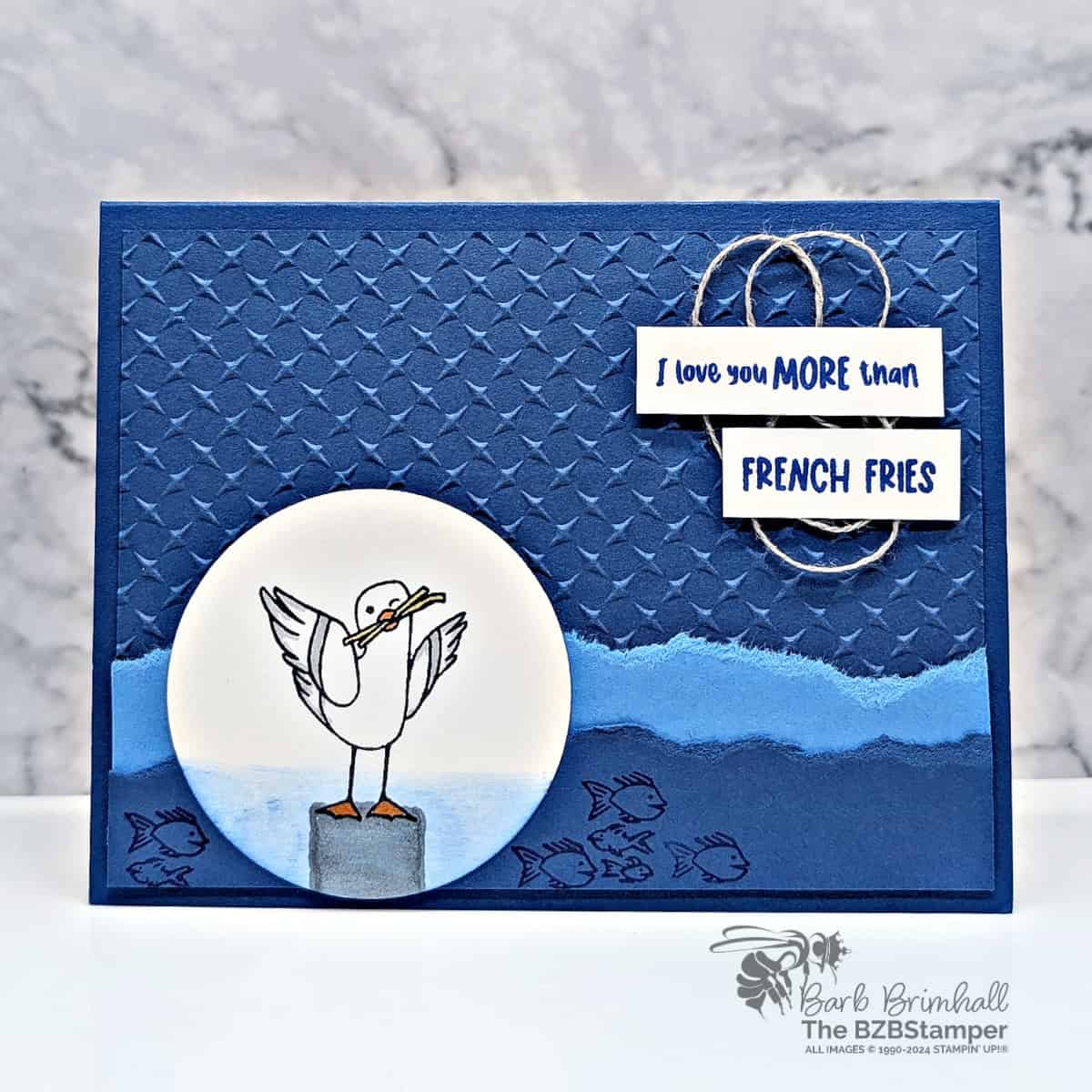 I Love You More Than French Fries Seagull Card featuring a seagull eating French Fries.  Card is in blues with an embossed background and fishies swimming in the sea.