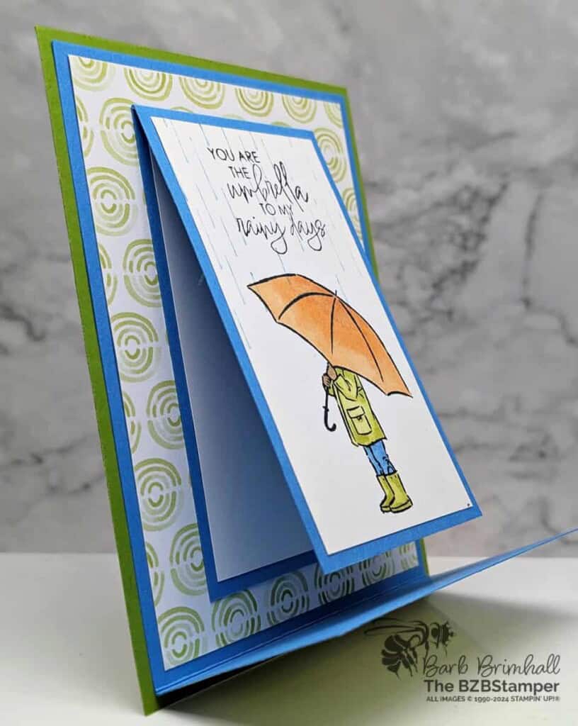Fun Fold with the Umbrella Days Stamp Set 5 Fun Fold with the Umbrella Days Stamp Set in blues, greens and oranges, with someone holding an umbrella and a "you are the umbrella to my rainy days" sentiment.
