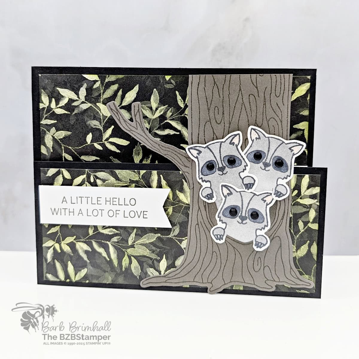 Cute Hello Card using the Peekaboo Forest Bundle 1 Cute Hello Card using the Peekaboo Forest Bundle featuring 3 raccoons, a tree with branches and leaves, in gray, brown and green. Sentiment is "A little hello with a lot of love."