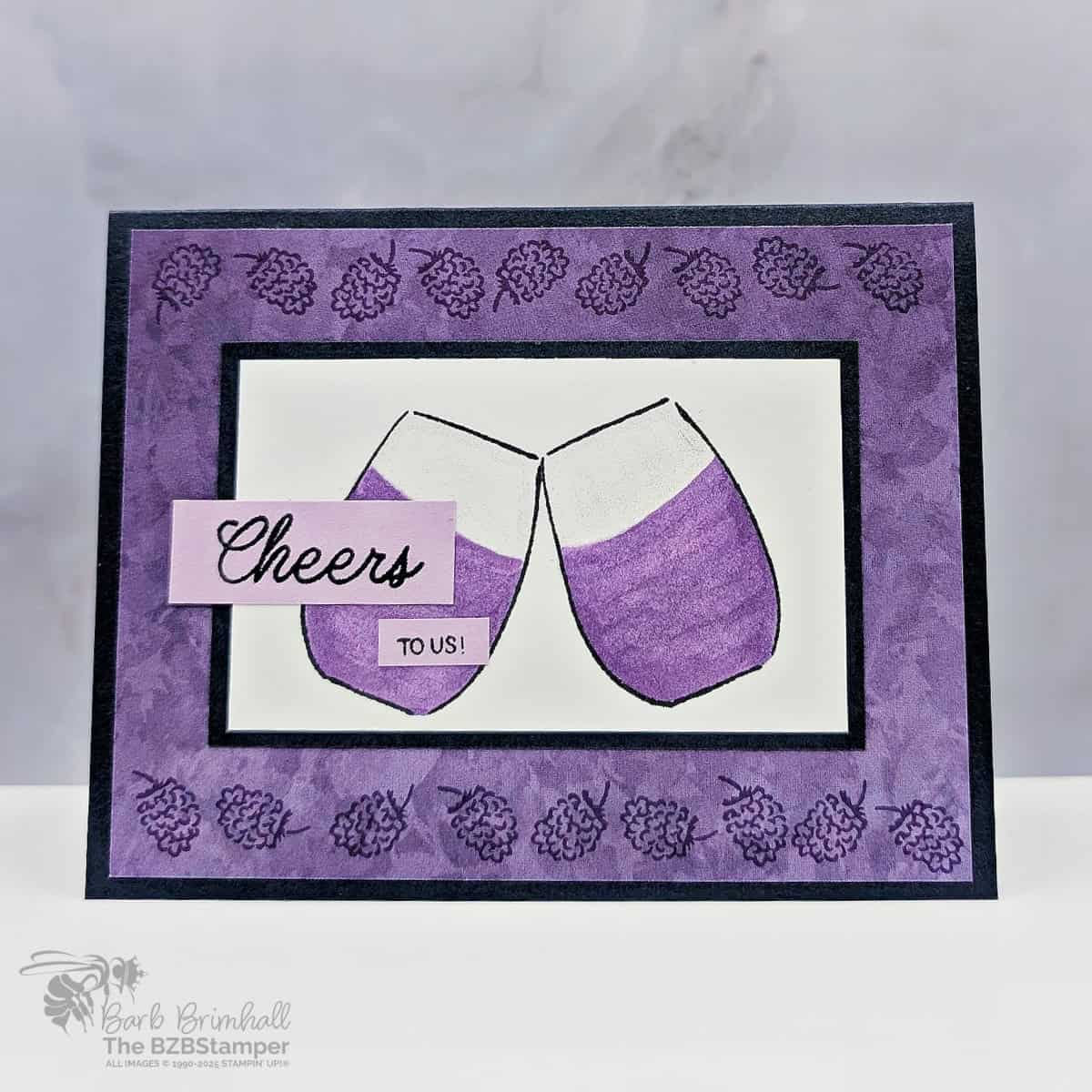 Cheers to Us with the Cheers and Sips Stamp Set in purples and dark navy blue, featuring 2 wine glasses clinking together and a "cheers to us" sentiment.