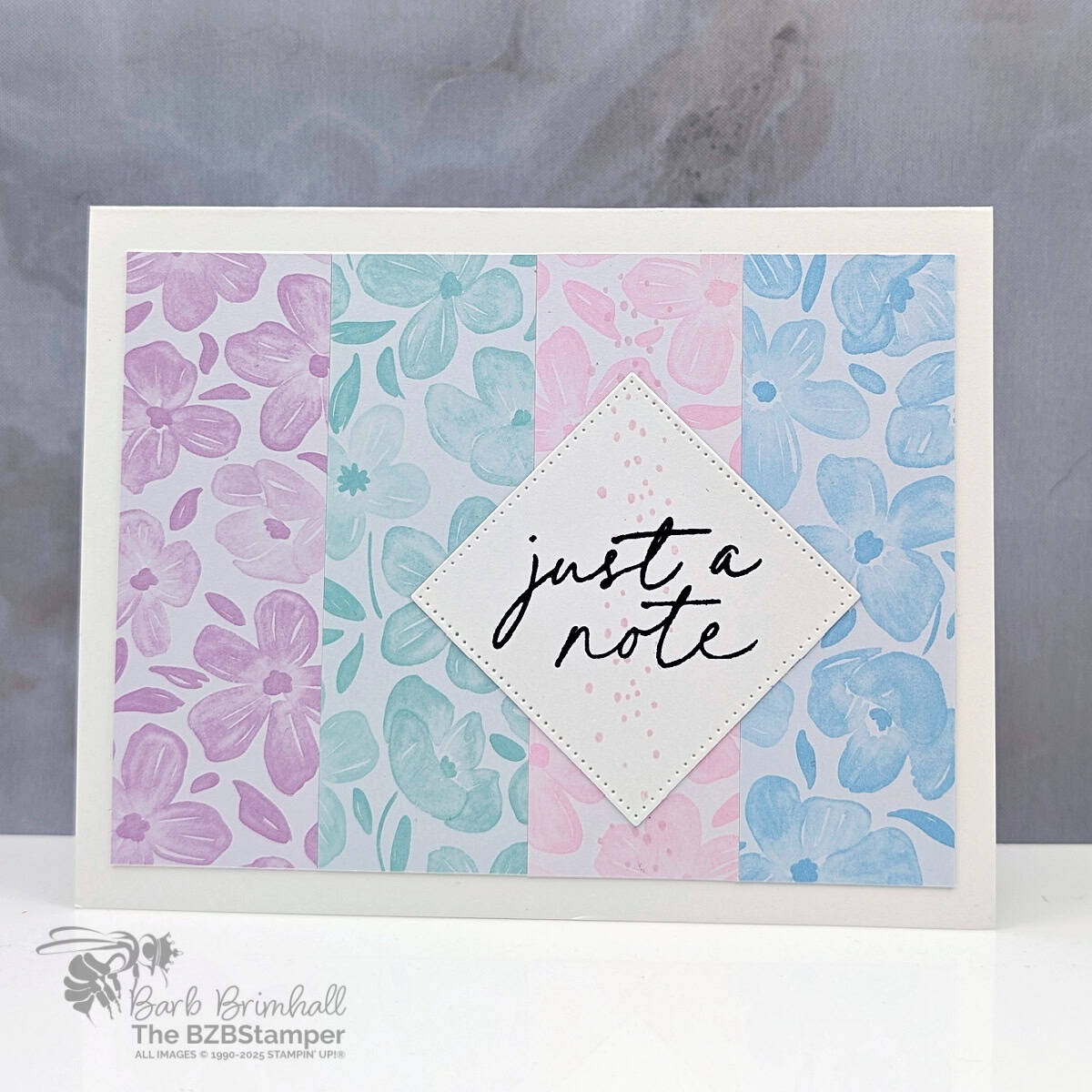 Just a Note with the Notes and Totes Stamp Set 1 Just a Note with the Notes and Totes Stamp Set with strips of pretty paper in blues, pinks and purples and a "Just a Note" sentiment in black ink.