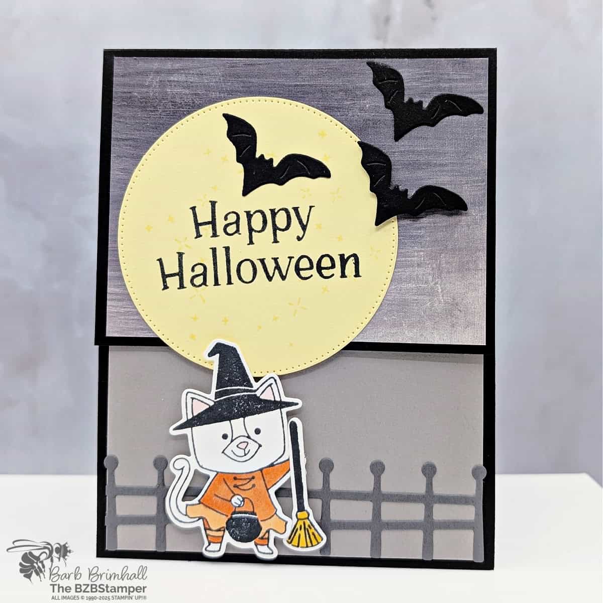 Coffee and a Card with the Spooky Halloween Bundle featuring a kitty witch carrying a pail and a broom against a fence in orange, yellow, and black.