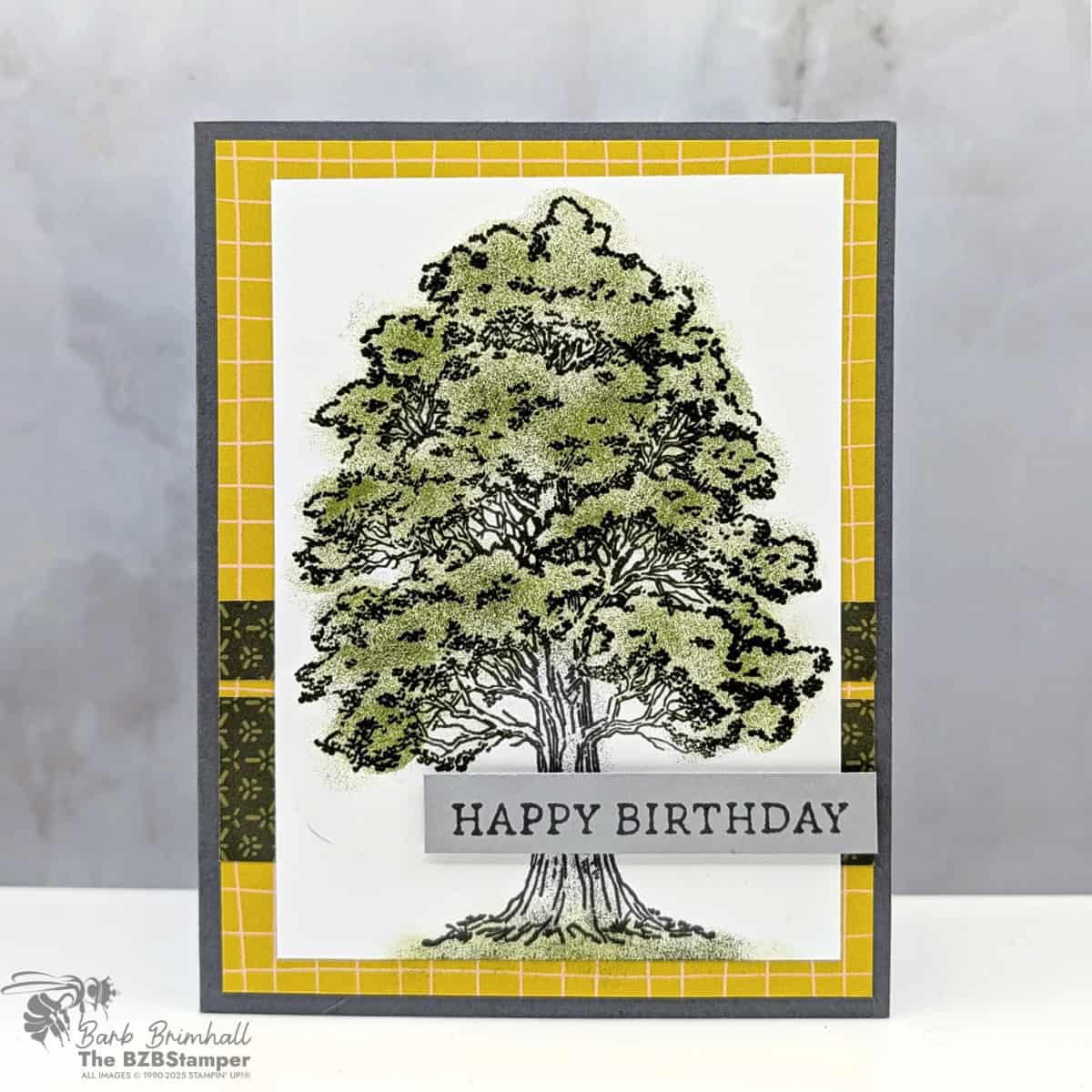 Masculine Birthday Card using the Autumn Trees Stamp Set featuring a large tree image colored with Mossy Meadow and Old Olive inks, layered on Darling Duckling yellow grid paper from Perfectly Pears Designer Paper, with Happy Birthday sentiment on gray cardstock.