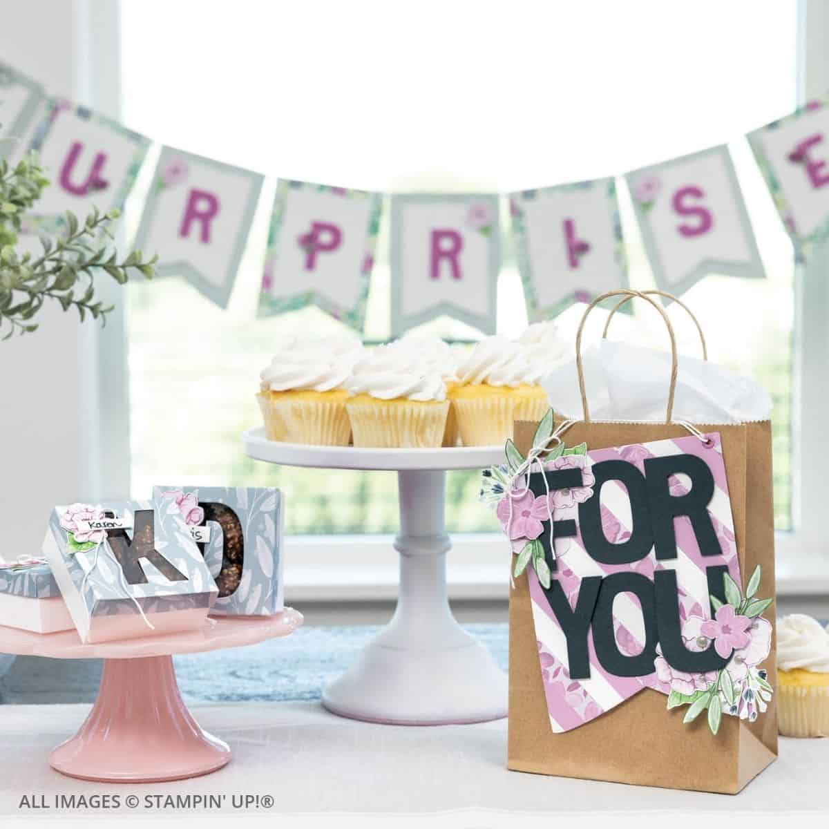 Building Relationships Through Cardmaking 3 Building Relationships Through Cardmaking. A birthday party scene with a handmade “For You” gift bag, coordinating mini treat boxes, and a “Surprise” banner in soft pinks and greens. Cupcakes and paper-crafted décor add a personal handmade touch to the celebration.